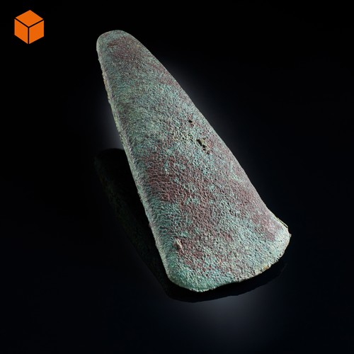Kupferbeil, das Beil ist flach und schmal, es läuft an einer Seite leicht spitz zu, es hat eine grüne Farbe aufgrund des oxidierten Kupfers.