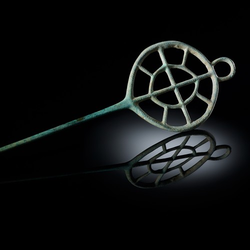 Nadel aus grüner Bronze, an einem Ende verziert mit einem großen, doppelten Speichenrad.