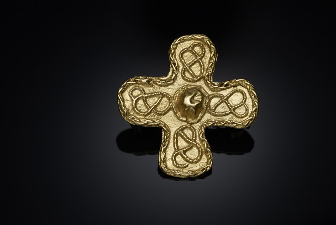 Goldene Fibel in Kreuzform, die vier Kreuzarme sind gleich lang.