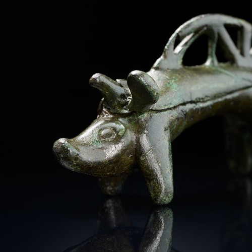 Kleine Figur aus grünlicher Bronze, die das stilisierte Aussehen eines Ebers hat.