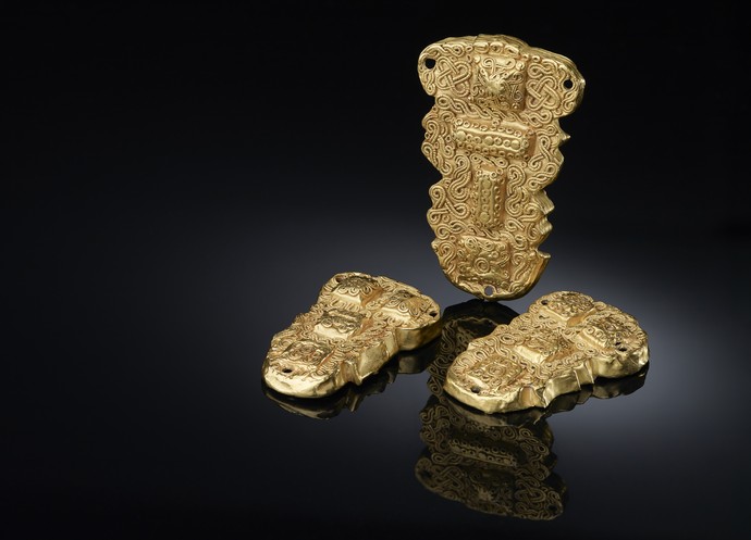 Drei goldenen Taschenbeschlägen, die mit komplizierten und miteinander verwobenen Mustern verziert sind.