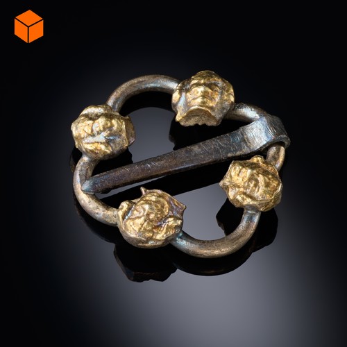 Kleine silberne Ringbrosche bestehend aus einer Silberspange, auf die vier feuervergoldete, sehr kleine Männerköpfe aufgelötet sind.