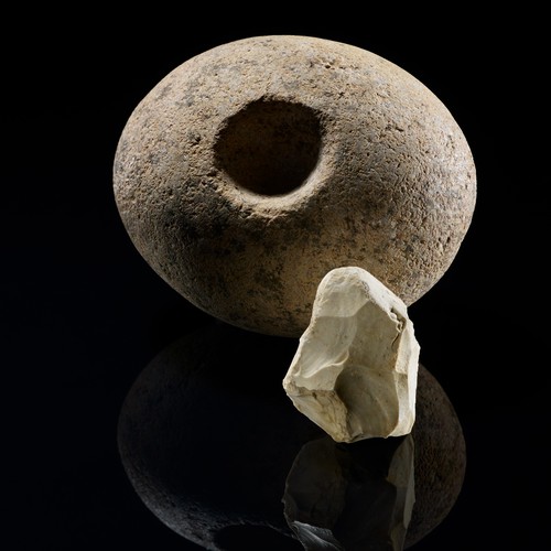Geröllkeule und ein Bohrer, die Keule ist rund, leicht rötlich mit einem Loch, der Bohrer ist ein kleiner spitzer und weißer Stein.