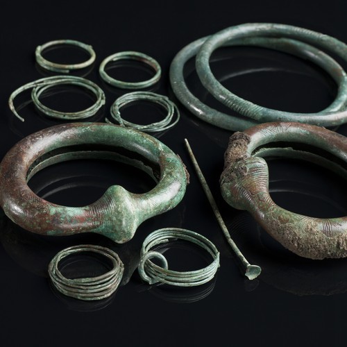 Verschiedene Schmuckgegenständen aus grünlicher Bronze, darunter Armringe.