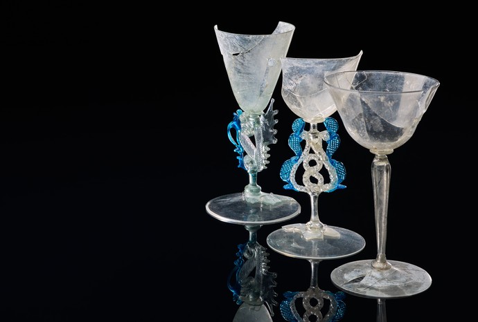 Drei feine Glaskelche mit geschwungener Form, von denen zwei Exemplare aufwendig gestaltete Stiele mit blauen Glaselementen aufweisen.