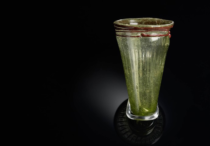 Unförmiger grüner Glasbecher, verziert mit einem roten Glasfaden an der Mündung.