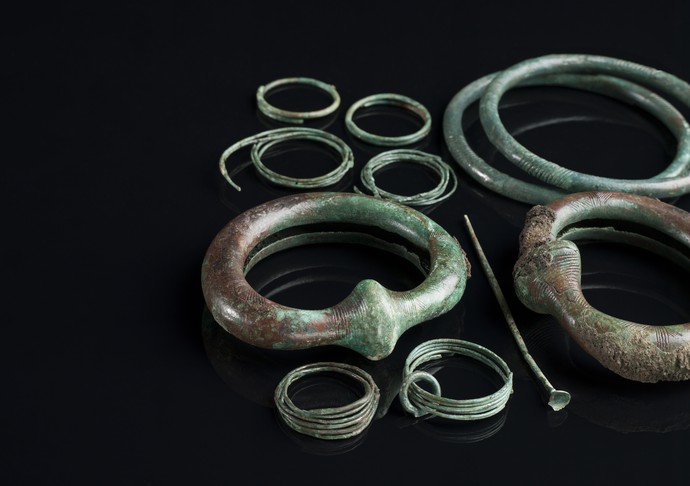 Verschiedene Schmuckgegenständen aus grünlicher Bronze, darunter Armringe.